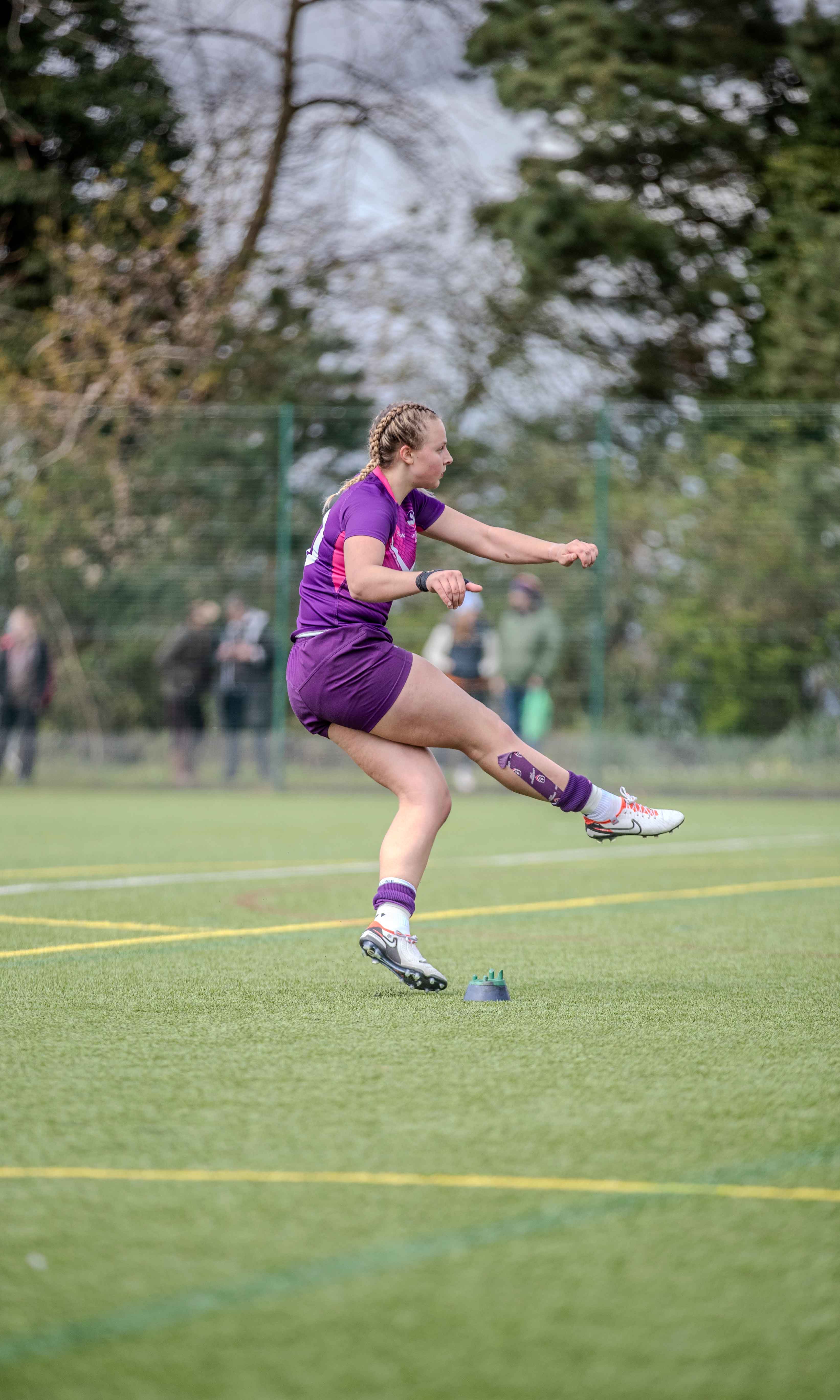 A loughborough students women's player kicking the ball in a match
